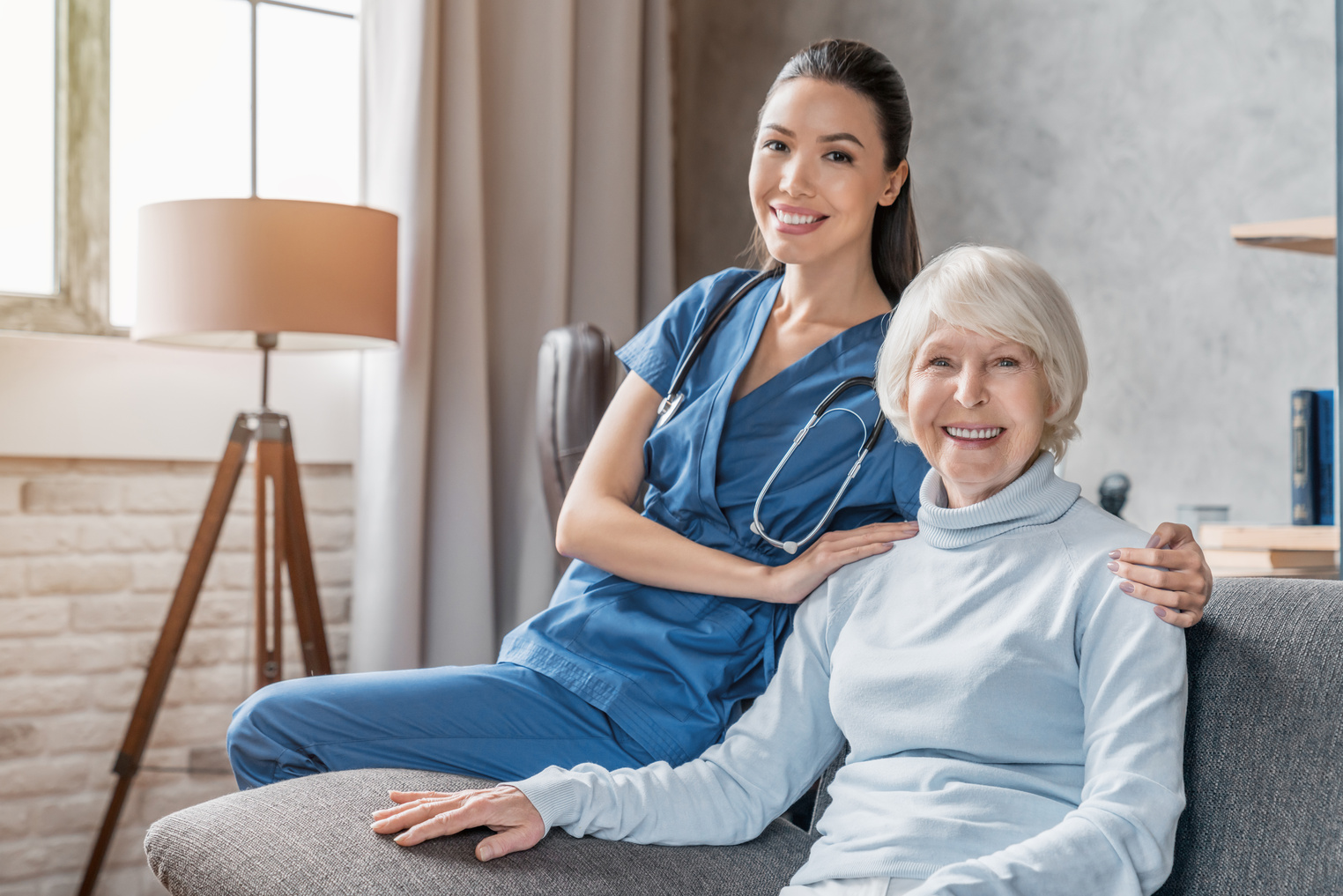 Portrait of happy elderly woman with nurse at home